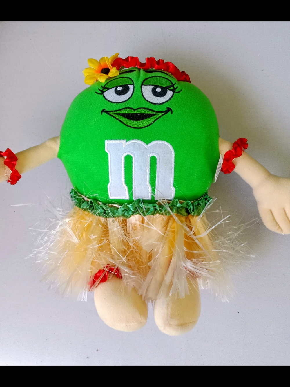 M&M'S Green Plush Hula Doll with Yellow Skirt and Red Flower Accents.Collectible